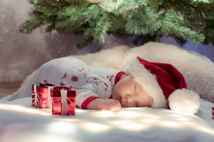 baby sleeping under christmas tree